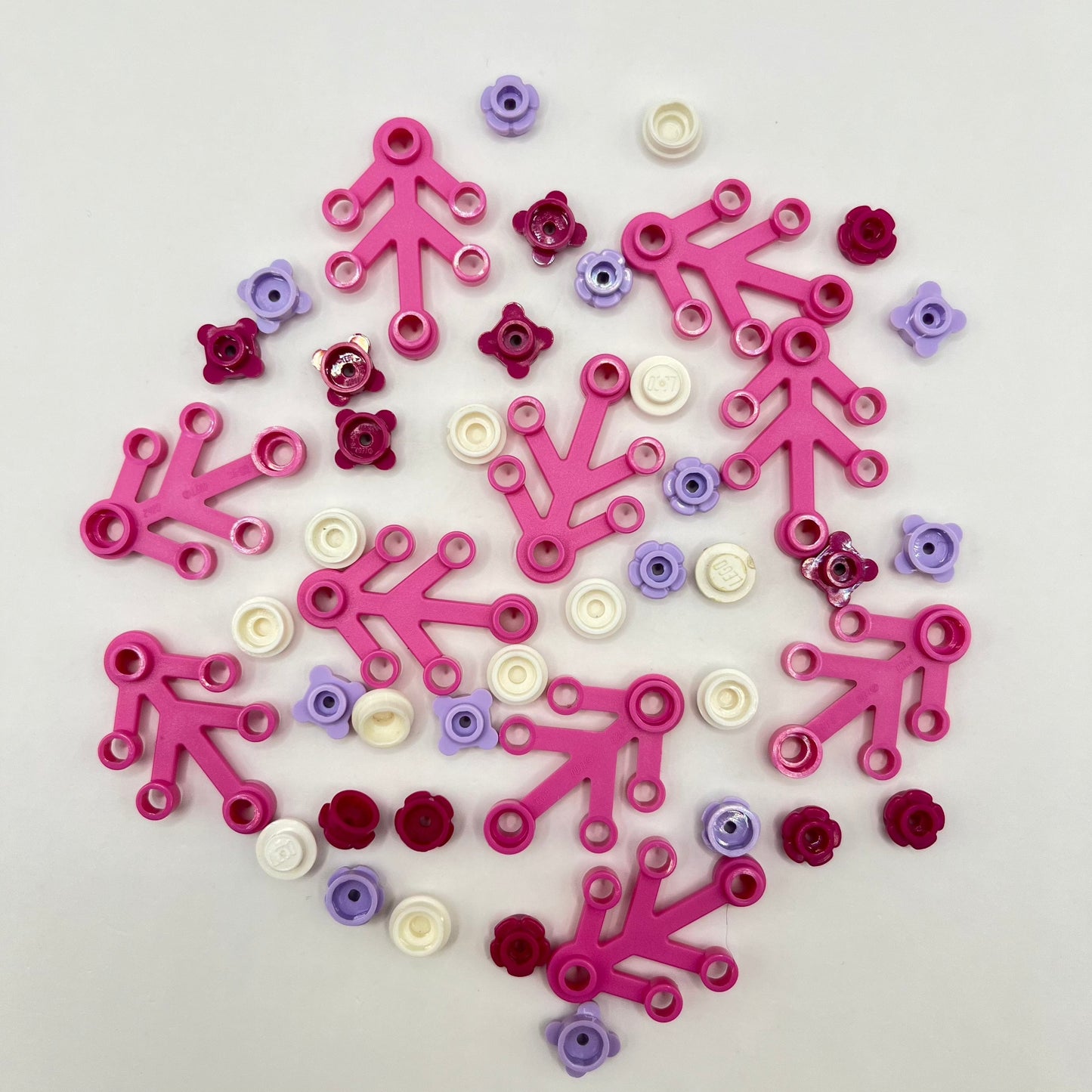 Decorative LEGO Christmas wreath made of interlocking pink, purple, and white pieces on a light grey background