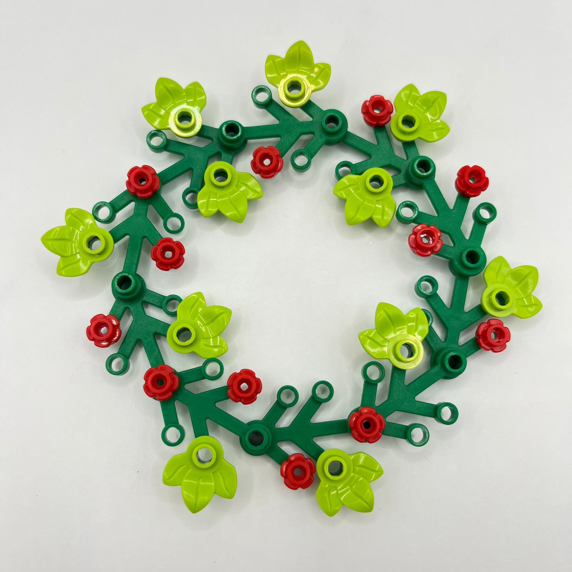 Decorative LEGO Christmas wreath made of green, red, and yellow pieces on a white background